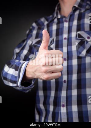 Man in checkered shirt showing thumbs up sign. Grey background Stock Photo