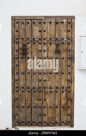 An old antique wooden door with wrought iron ornate reinforcements in Cordoba, Andalusia, Spain Stock Photo