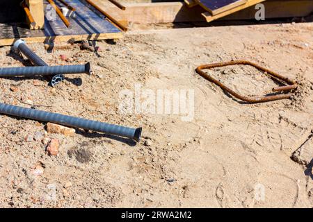 A few screws, holders for bridge molds placed on the ground, in background is wooden molds in row, bridge skeleton at construction site. Stock Photo