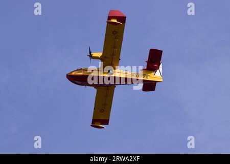 View from the ground of a Canadair CL-415 type seaplane (43 group) of the Kingdom of Spain crosses the sky to refill water in the port Stock Photo