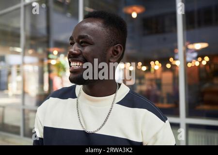 Candid close up portrait of smiling African American man looking away in city, copy space Stock Photo