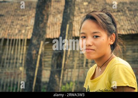 Damak, Nepal, circa May 2012: Brown-haired girl in yellow t-shirt and with simple necklace at Nepali refugee camp in Damak, Nepal. Documentary Stock Photo