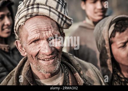 Dolpo, Nepal, circa May 2012: Old native man with little beard wears brown headcloth and jacket and frowns to photocamera in Dolpo, Nepal. Stock Photo