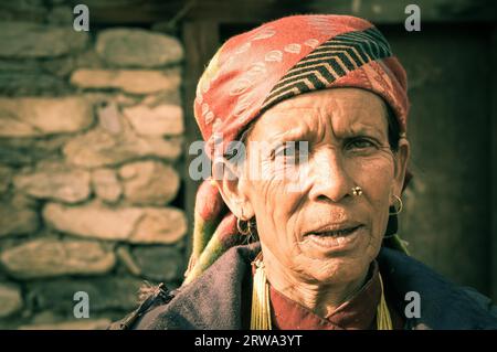 Beni, Nepal, circa May 2012: Small girl with short brown hair and brown eyes wears earrings and blue and yellow jacket and stands near her smiling Stock Photo