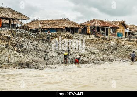 Sunderban, Bangladesh, circa July 2012: Photo of six native men working in mud near their houses and river in Sunderban, Bangladesh. Documentary Stock Photo