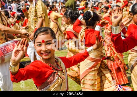 Guwahati, Assam, circa April 2012: Dancing girl in red and yellow sari with red dot on forehead smiles during performance at traditional Bihu Stock Photo