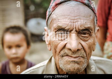 Damak, Nepal, circa May 2012: Old frowning man with beard and wrinkles on his face at Nepali refugee camp in Damak, Nepal. Documentary editorial Stock Photo