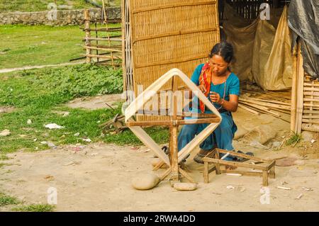 Damak, Nepal, circa May 2012: Native woman in blue clothes and colourful scarf sits outside and works at Nepali refugee camp in Damak, Nepal. Stock Photo