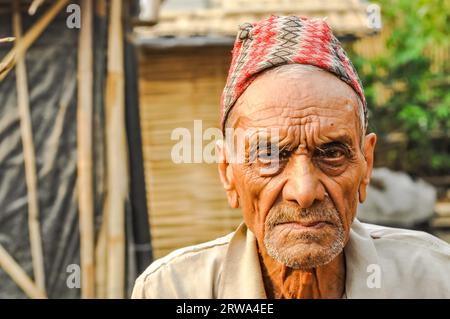 Damak, Nepal, circa May 2012: Old man with wrinkled face with cap on his head frowns and looks sadly to photocamera at Nepali refugee camp in Damak Stock Photo