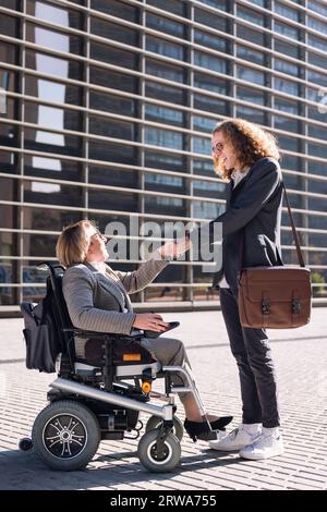 man and woman using wheelchair shaking hands Stock Photo