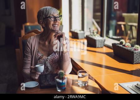 Mature woman is sitting in cafe and relaxing. Stock Photo