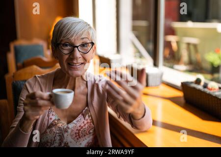 Mature woman is drinking coffee in cafe. Stock Photo