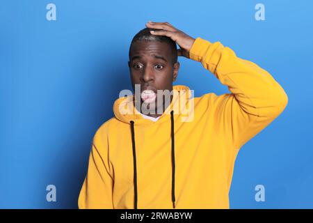 Confused black guy touching his head, blue background Stock Photo