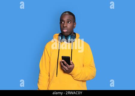 Photo of concentrated man focused on recollecting necessary facts browsing through telephone he holds isolated vivid color blue background Stock Photo