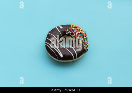 Messy chocolate doughnut isolated on blue background, after some edits. Stock Photo