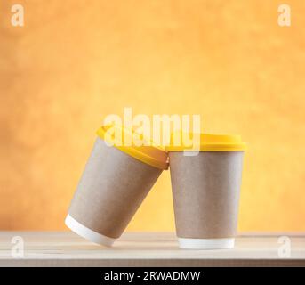 Two takeaway coffees on table and on a bright gold background. Concept of love and tenderness. Stock Photo