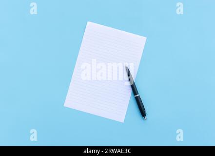 Blank white paper and pen isolated on blue background. After some edits. Stock Photo