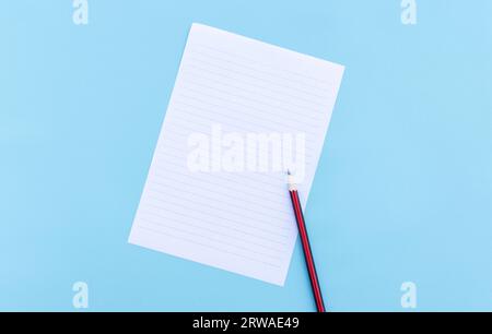 Blank white paper and pencil isolated on blue background. After some edits. Stock Photo