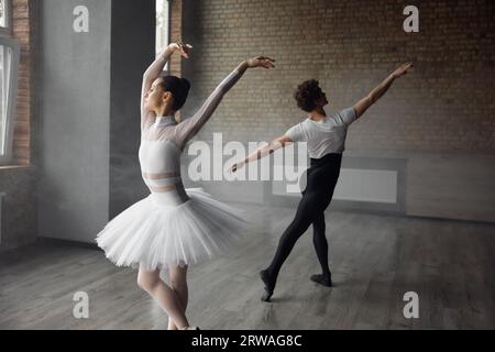 Two young ballet dancers wearing costume practicing together in studio class Stock Photo