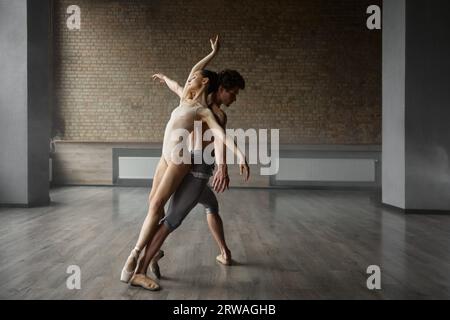 Young professional acrobats partners embracing standing back to back Stock Photo