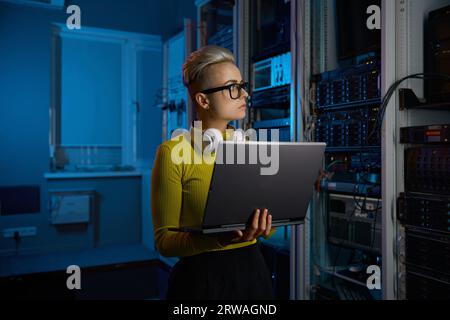 Portrait of concentrated woman coder solving problem in data center Stock Photo