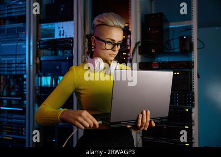IT woman connecting internet network cable to laptop in server room Stock Photo
