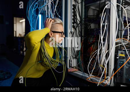 Confused female data center technician inspecting computer system and hardware Stock Photo