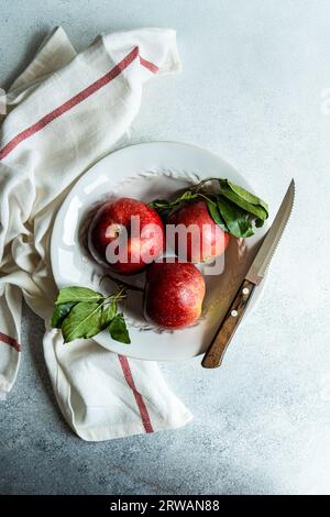 Overhead view of a plate with three ripe red apples on a table Stock Photo
