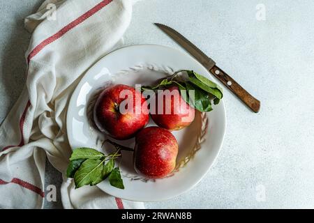 Overhead view of three ripe red apples on a plate Stock Photo