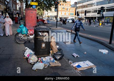 Local people walk beside cycle lane superhighway litter in Aldgate / Whitechapel on 16th August 2023 in London, United Kingdom. In this area there are often overflowing bins and rubbish and commercial waste left on the pavement. A cycle Superhighway is a long cycle path and part of the Cycleway network coordinated by TfL. It is a popular route with both commuter and leisure cyclists, passing a number of major destinations in London along its route. For almost the entire route, cyclists are separated from other traffic in segregated cycle lanes, and cycling infrastructure has been provided at m Stock Photo