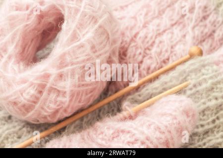Yarn and knitting needles, top view. Grey and pink wool thread with needles. Knitting crochet. Knitted pattern. Needlework concept. Handmade pullover. Stock Photo