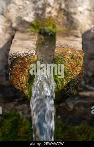 Closeup of a mossy limestone water trough with clean water flowing out of it. Sacred karst spring of hermit St.Ivan at Svatý Jan pod Skalou, Czechia. Stock Photo