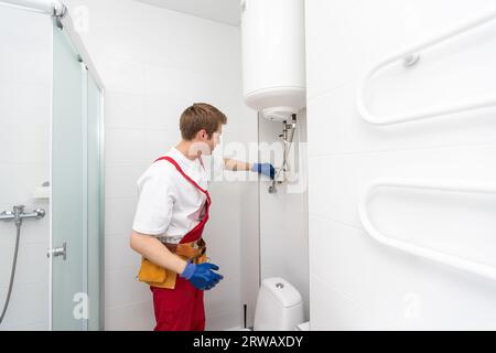 Closeup of plumber using screwdriver while fixing boiler or water heater, working on heating system in apartment Stock Photo
