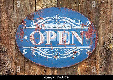 Come in we are open sign on a weathered old wooden background Stock Photo