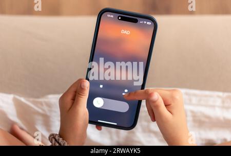 Close up of child hands holding phone with Dad's incoming call on display. Stock Photo