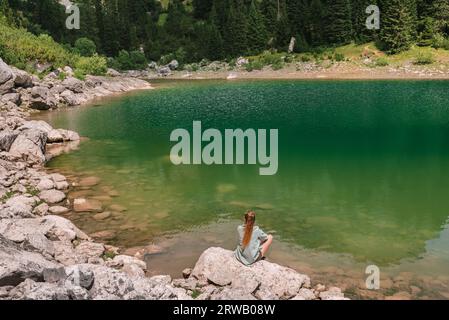 Woman Sitting on Rock by Mountain Lake in Durmitor Stock Photo