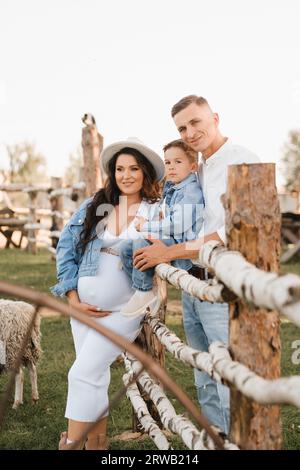 Stylish family in summer on a village farm with sheep. Stock Photo