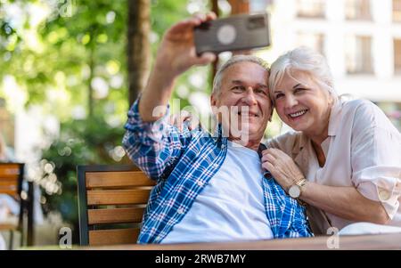 Senior couple sitting at a table in a cafe and using mobile phone Stock Photo