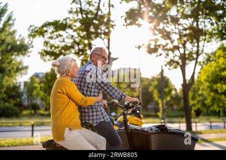 Senior couple riding cargo bike in the city Stock Photo