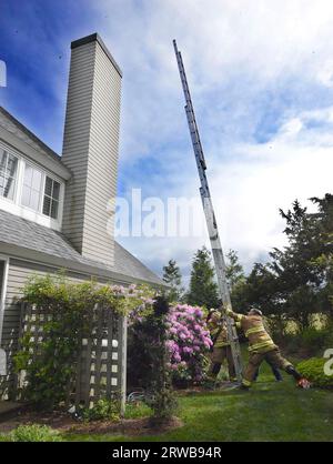 DFD1 chimmneyfire 44 NorthShoreDr06-04-2023 Capt's Snell (Left) amd Capt Costa Laddering 35 foot ladder to the top of Chimmney Stock Photo