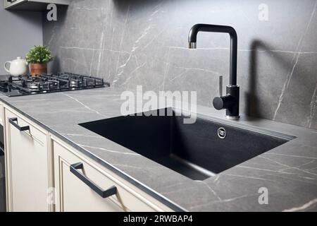 Compact undermount sink. Kitchen sink area with black square matte sink tap in contemporary style. Matte black and stoneware kitchen design. Black Stock Photo