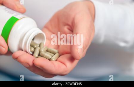 Hand holding medicine pill, emphasizing dose and healthcare. Close-up shot. Stock Photo