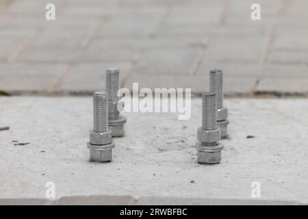 Closeup Anchorage bolt and nut which embedded in concrete structure etail of bolts. Steel plate based on anchor bolts on the concrete pillar. Bolts ba Stock Photo