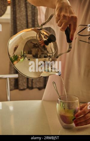 Woman pouring hot coffee in cup in the morning from pot. Housewife at home making fresh ground coffee in kitchen for breakfast, drinking, grinding cof Stock Photo