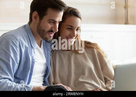 Smiling woman and man using laptop, looking at screen together Stock Photo