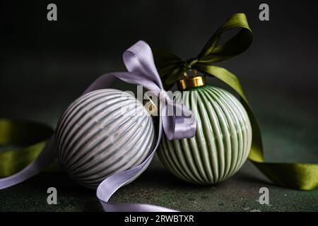 Balls as sign of Christmas decorated with ribbons and placed on green surface against dark background Stock Photo