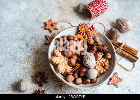 Top view of plate of heap of chestnuts with tasty Christmas cookies placed on table near spool of red thread Stock Photo