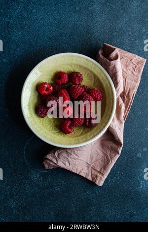 From above of bowl with ripe raspberries and placed on a dark concrete table Stock Photo
