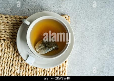 From above of white stylish cup of hot aromatic Green tea with tag placed on with on concrete table Stock Photo