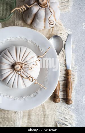 Top view of autumnal table setting with white pumpkin on plate placed on table near cutlery and glass Stock Photo